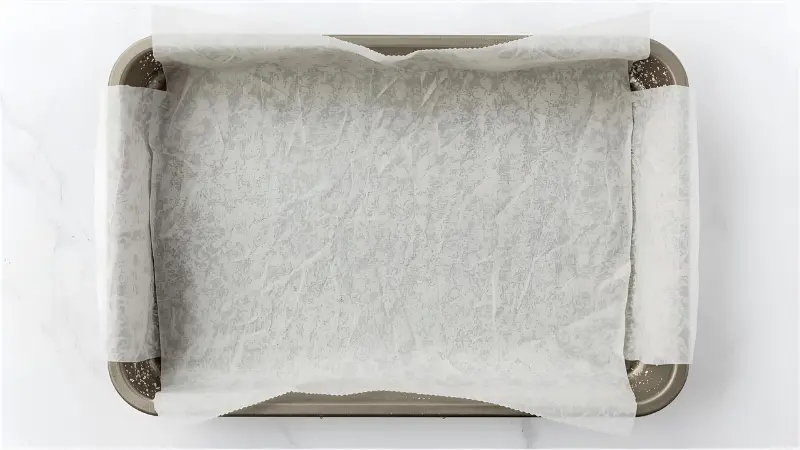1. Preheat your oven to 350°F (175°C) and line your pan with parchment paper, leaving overhang on two sides for easy lifting.